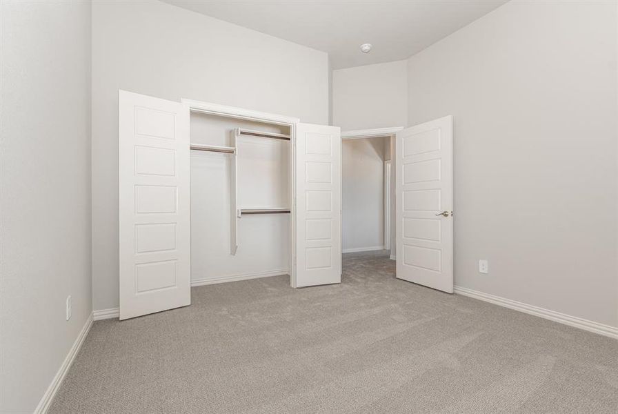 Unfurnished bedroom featuring light carpet and a closet