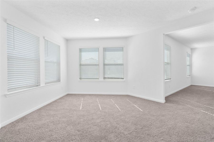 This spacious sitting room, just off the primary bedroom, is perfect for a reading nook, workout space, or a home office. It features large windows with privacy blinds, recessed lighting and carpet flooring!