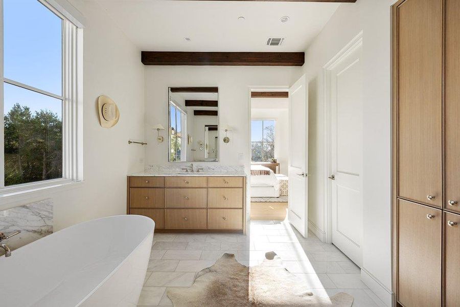 Bathroom with ensuite bath, a freestanding bath, vanity, and beamed ceiling
