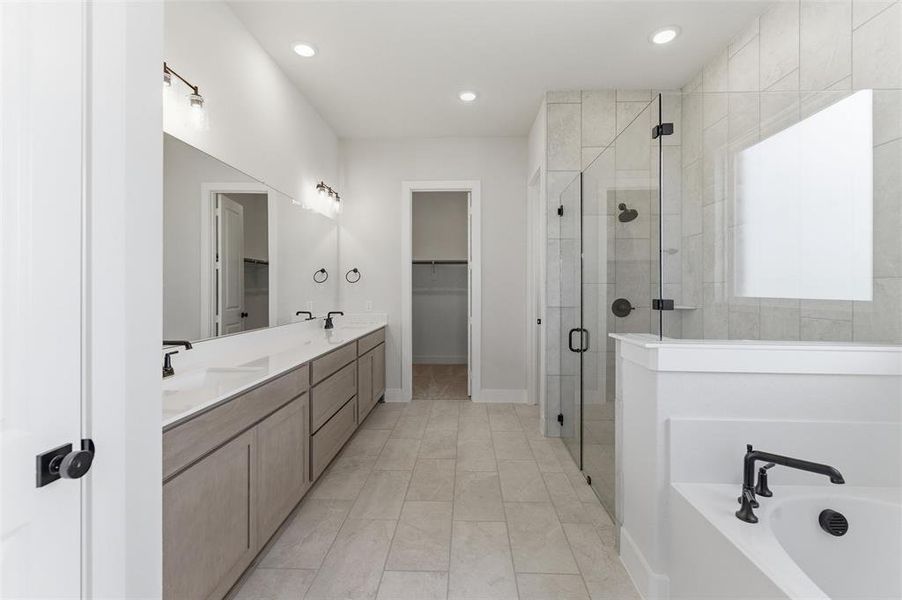 Bathroom featuring a stall shower, double vanity, recessed lighting, a garden tub, and a walk in closet Bathroom featuring a stall shower, double vanity, recessed lighting, a garden tub, and a walk in closet