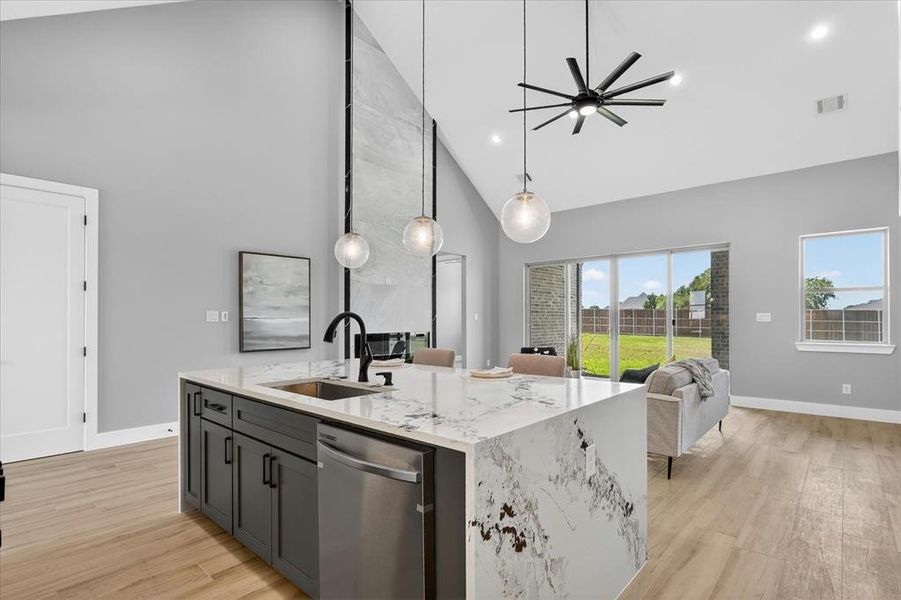 Kitchen island with waterfall countertop, black cabinetry, and undermount sink