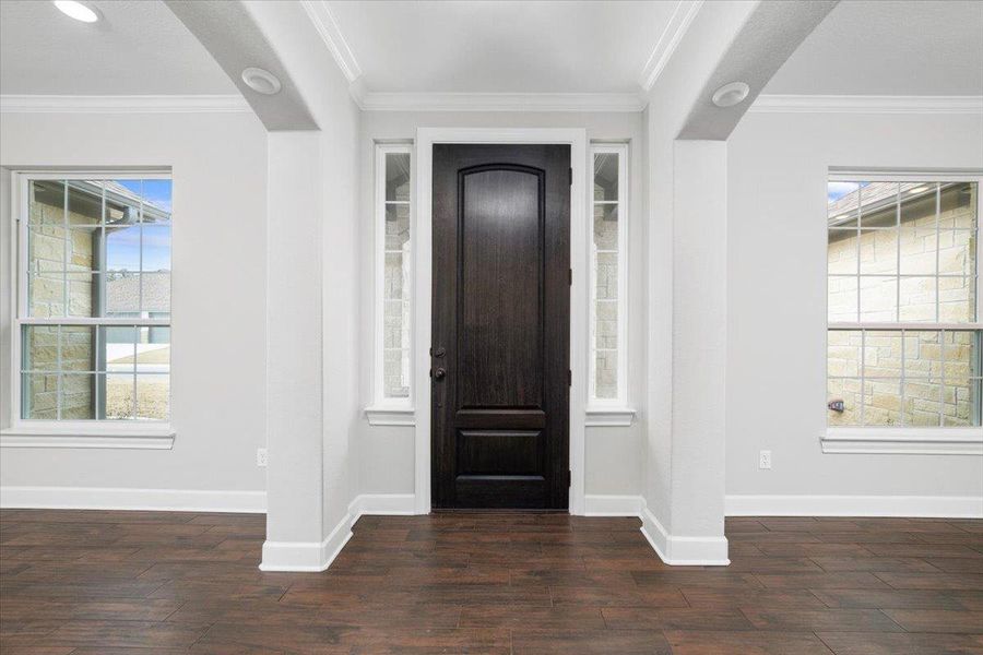 Foyer entrance with baseboards, dark wood-style flooring, and ornamental molding Foyer entrance with baseboards, dark wood-style flooring, and ornamental molding