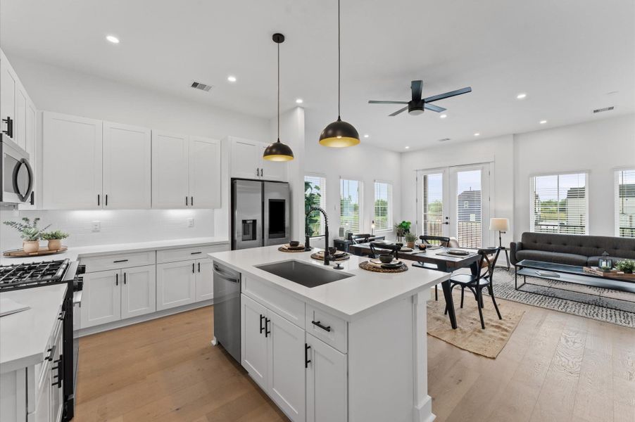 This centrally positioned kitchen island serves as a stylish anchor within the open-concept layout, offering clear sightlines to the dining area and living space. Its placement encourages seamless interaction, whether prepping meals or entertaining guests, while natural light pours in through the windows. The island’s sleek design and functional surface make it a hub of activity tying together comfort and sophistication.