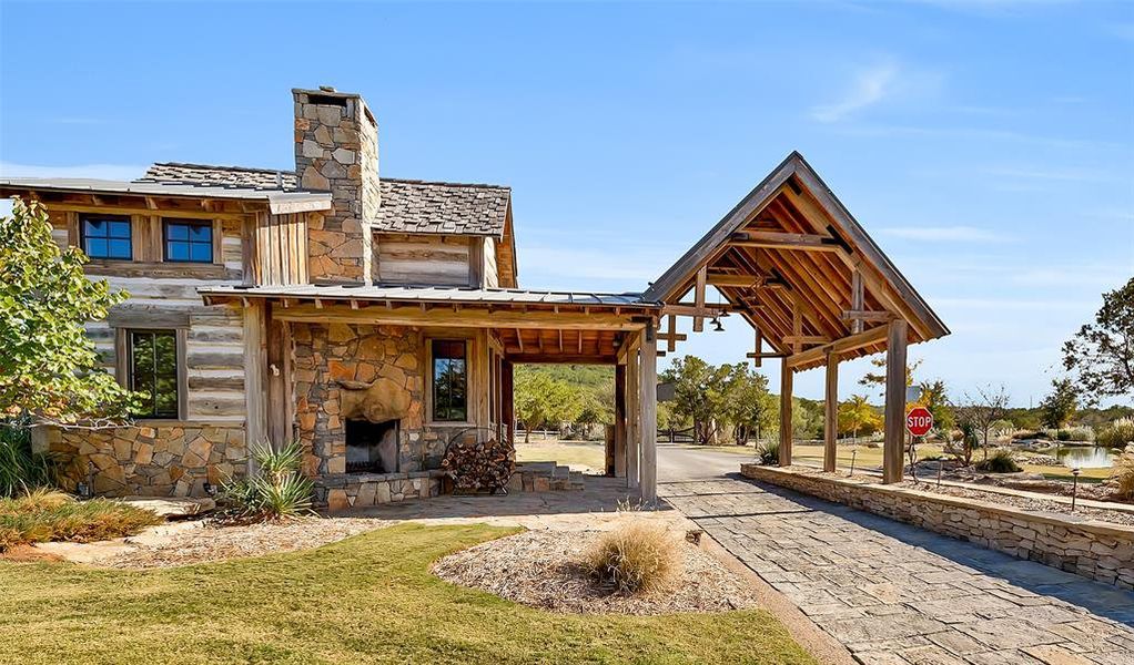 Rear view of house with covered porch, an outdoor stone fireplace, a chimney, stone siding, and a metal roof Rear view of house with covered porch, an outdoor stone fireplace, a chimney, stone siding, and a metal roof