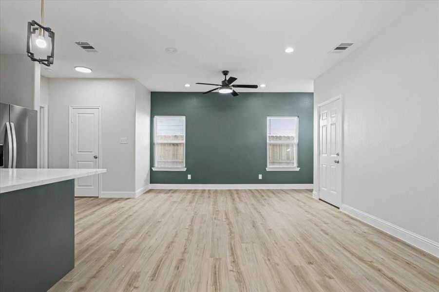 Unfurnished living room with ceiling fan and light wood-type flooring