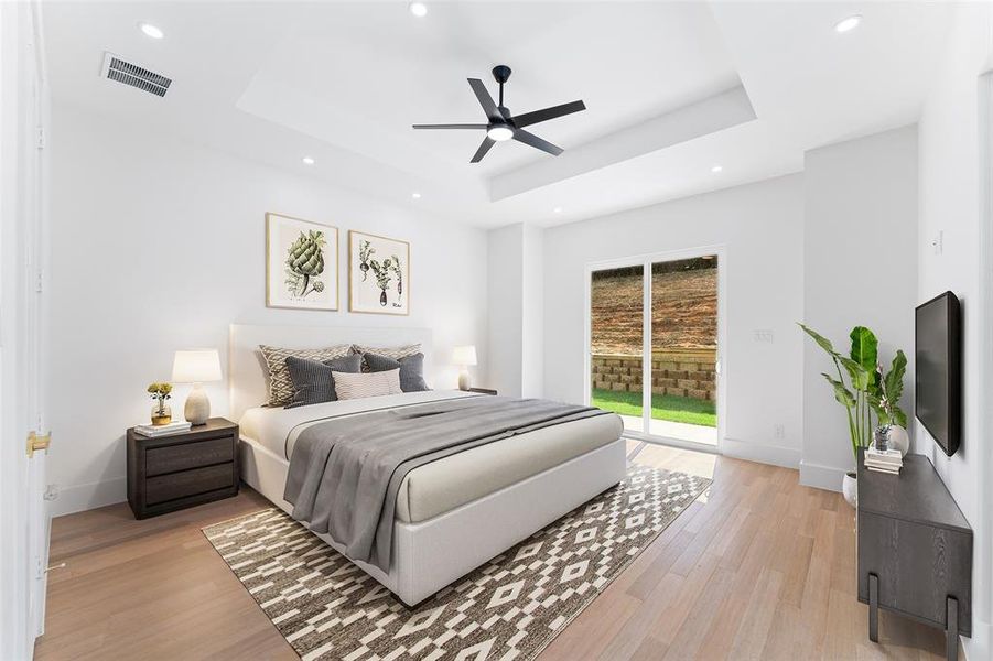 Bedroom featuring light wood finished floors, access to exterior, ceiling fan, a tray ceiling, and recessed lighting