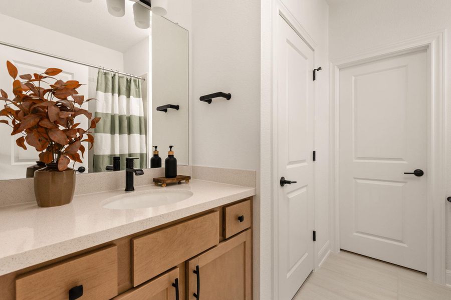 Bathroom vanity featuring a light-toned countertop, an undermount sink, and black fixtures