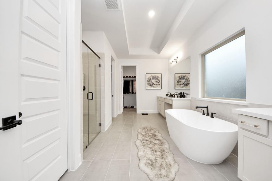 Luxurious primary bathroom with a freestanding tub, walk-in shower, dual vanities, and direct access to the walk-in closet.