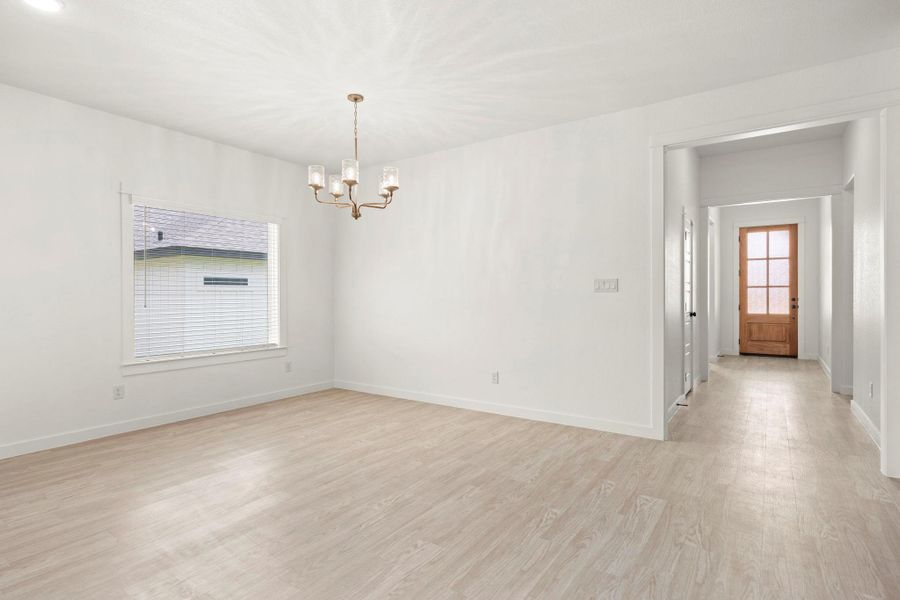 A refined bronze chandelier illuminates this spacious, airy room with light-toned flooring.