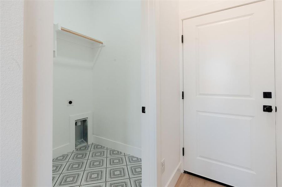Dedicated laundry room with electric dryer hookup, stylish accent floor tile