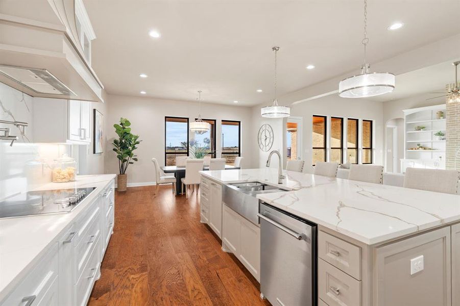 Kitchen with dishwasher, custom exhaust hood, decorative light fixtures, a large island, and white cabinets