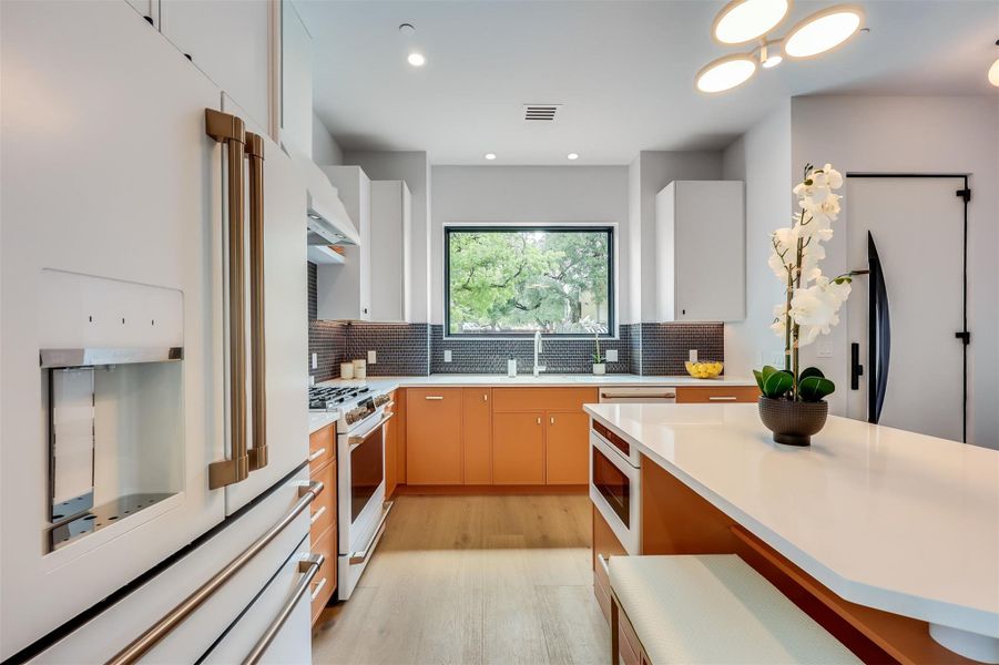Those bold orange cabinets aren't just a color choice; they’re a statement that this kitchen is built for high-energy mornings and long weekend brunches