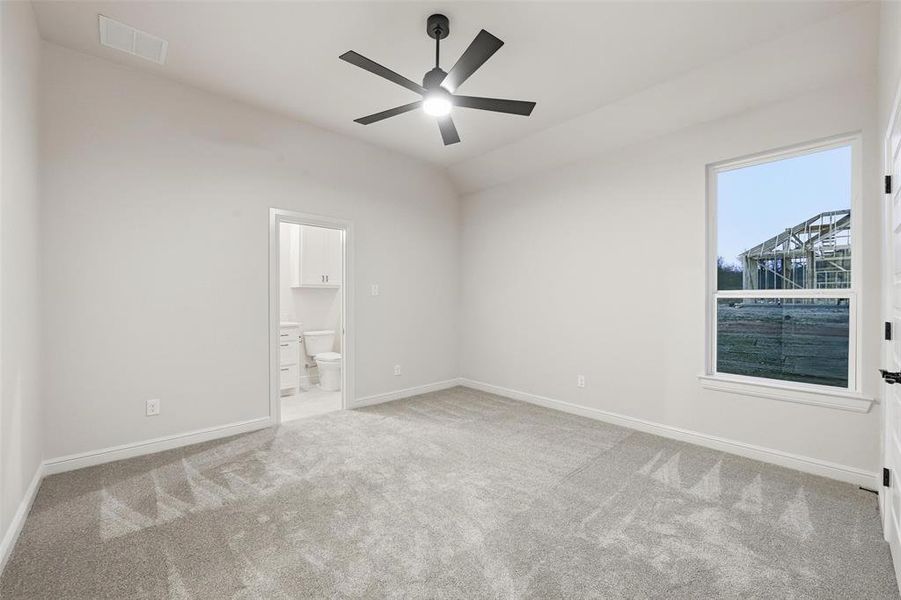 Unfurnished bedroom featuring light colored carpet, a ceiling fan, ensuite bath, and lofted ceiling Unfurnished bedroom featuring light colored carpet, a ceiling fan, ensuite bath, and lofted ceiling