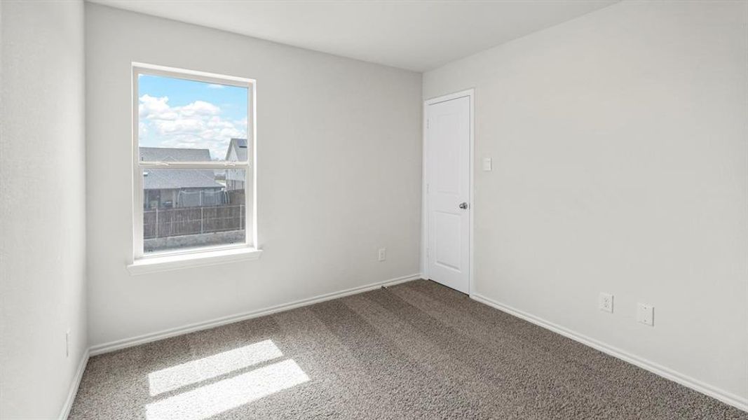 Bright room featuring neutral-toned walls, gray carpeting, and a window providing natural light