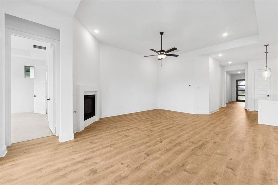 Unfurnished living room with a glass covered fireplace, recessed lighting, light wood finished floors, and ceiling fan Unfurnished living room with a glass covered fireplace, recessed lighting, light wood finished floors, and ceiling fan