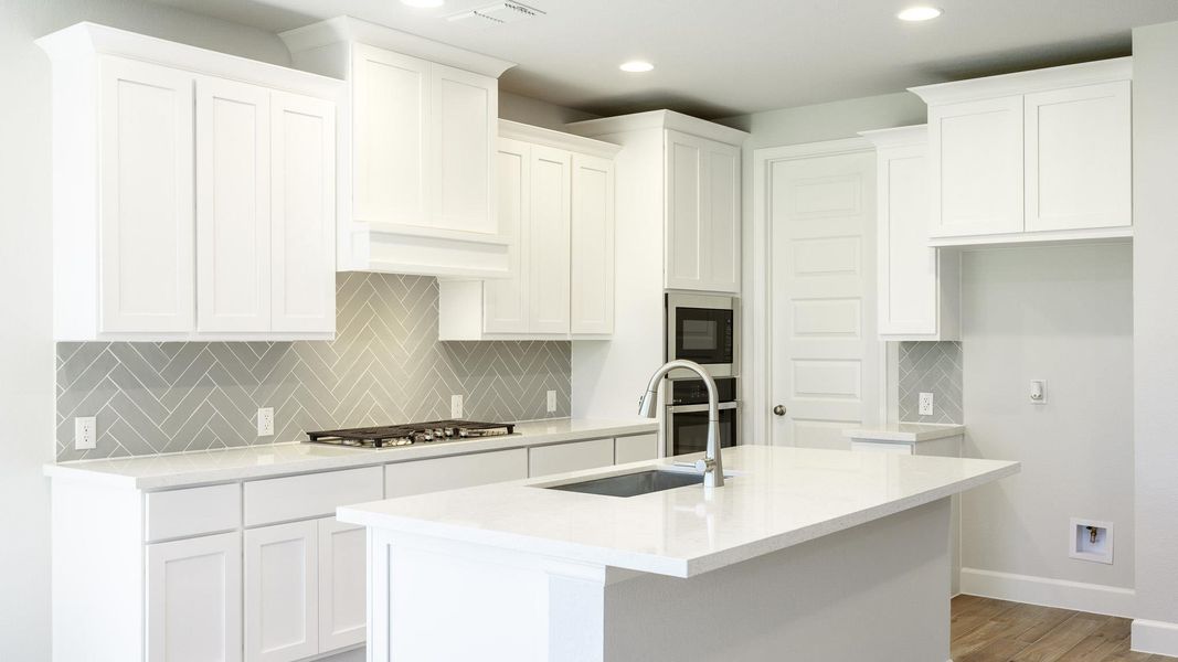 Kitchen featuring tasteful backsplash, light stone countertops, a center island with sink, white cabinetry, and recessed lighting Kitchen featuring tasteful backsplash, light stone countertops, a center island with sink, white cabinetry, and recessed lighting