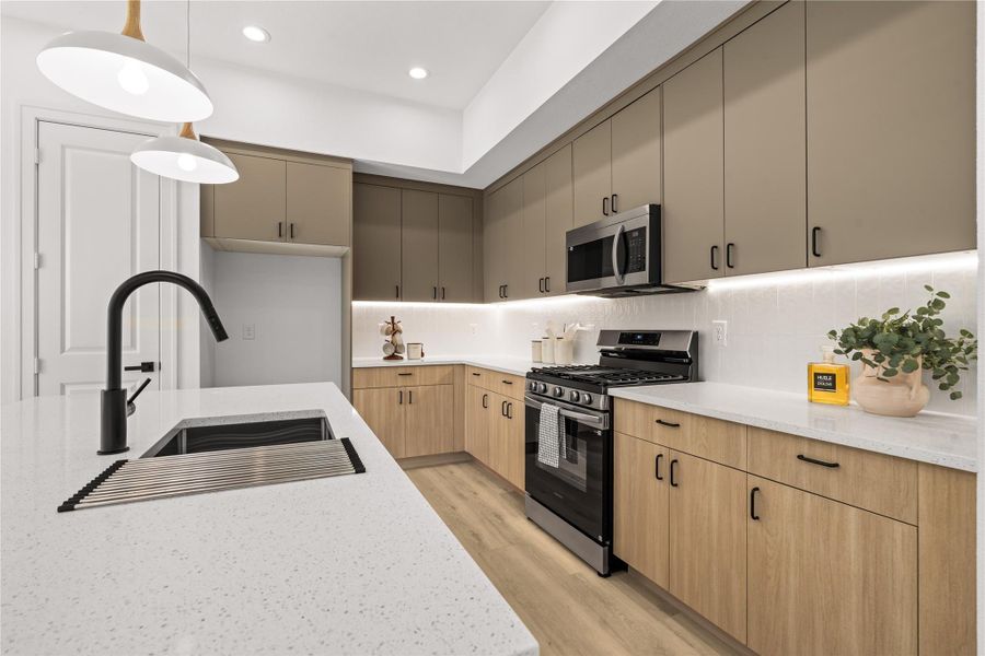 The two-tone cabinets provide plenty of storage space without cluttering the room. Matte black hardware accents the natural wood lower drawers and muted taupe upper cabinets, while under-cabinet LED lighting brightens up the white vertical tile backsplash.