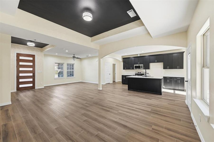 Unfurnished living room with arched walkways, light wood finished floors, a ceiling fan, and recessed lighting Unfurnished living room with arched walkways, light wood finished floors, a ceiling fan, and recessed lighting