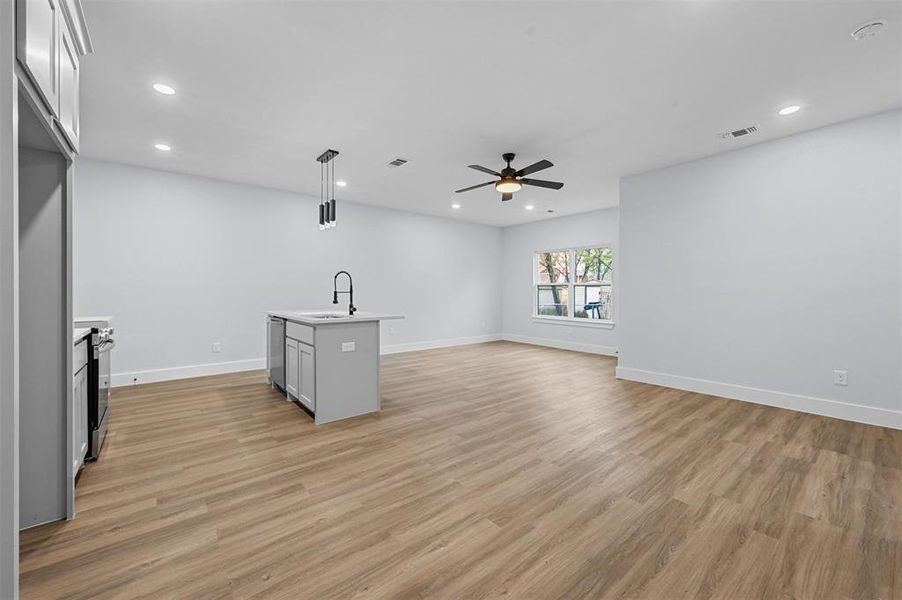 Unfurnished living room with a fireplace, light wood-type flooring, ceiling fan, and sink