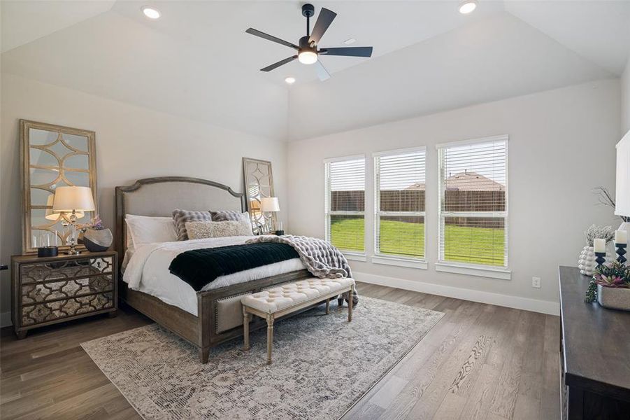 Vaulted ceiling with recessed lighting and a ceiling fan, three pane windows with horizontal blinds, wood-finish flooring, and a neutral color palette throughout