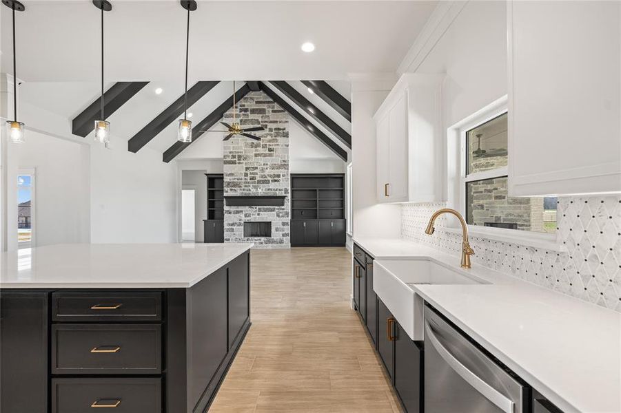 Kitchen with a fireplace, open floor plan, decorative light fixtures, dishwasher, and light stone countertops