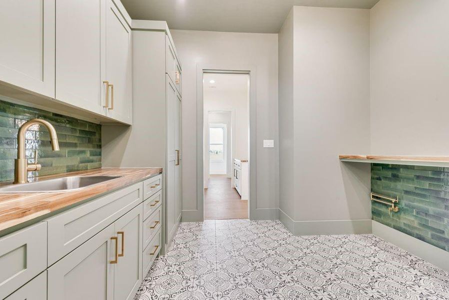 Laundry room with sink, folding area, dog feeding and water spigot at floor