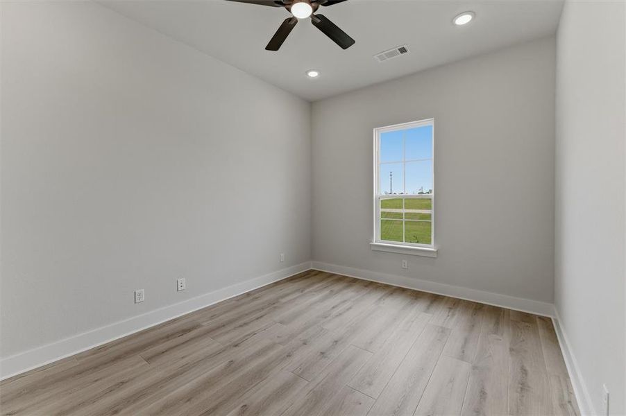 Bright interior space featuring a window with exterior views, wood-finish flooring, a ceiling fan, and recessed lighting