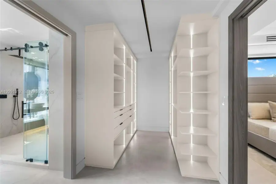 Custom walk-in closet featuring floor-to-ceiling built-in cabinetry, integrated vertical accent lighting, and multi-drawer storage units Custom walk-in closet featuring floor-to-ceiling built-in cabinetry, integrated vertical accent lighting, and multi-drawer storage units