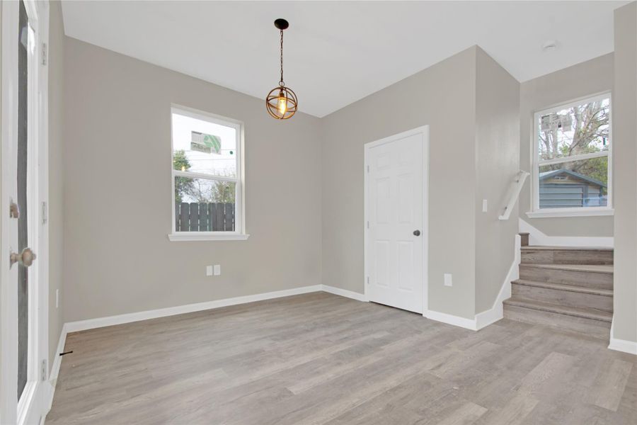 Unfurnished dining area with stairs and light wood finished floors