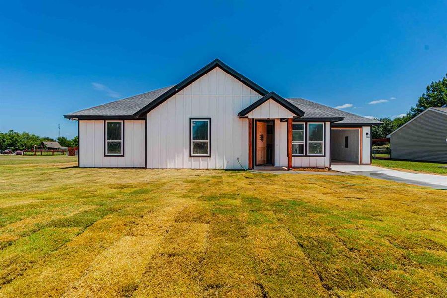 Modern inspired farmhouse with a shingled roof, a front lawn, and board and batten siding Modern inspired farmhouse with a shingled roof, a front lawn, and board and batten siding