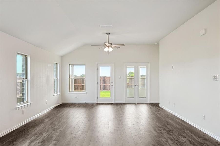 Empty room with ceiling fan, lofted ceiling, and dark hardwood / wood-style floors