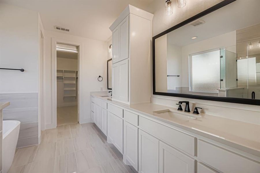 Full bath featuring double vanity, a walk in closet, a soaking tub, and a stall shower Full bath featuring double vanity, a walk in closet, a soaking tub, and a stall shower