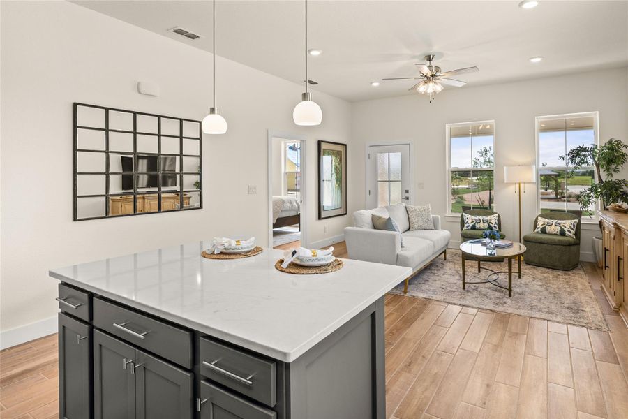 Kitchen featuring light wood finished floors, a kitchen island, pendant lighting, ceiling fan, and open floor plan