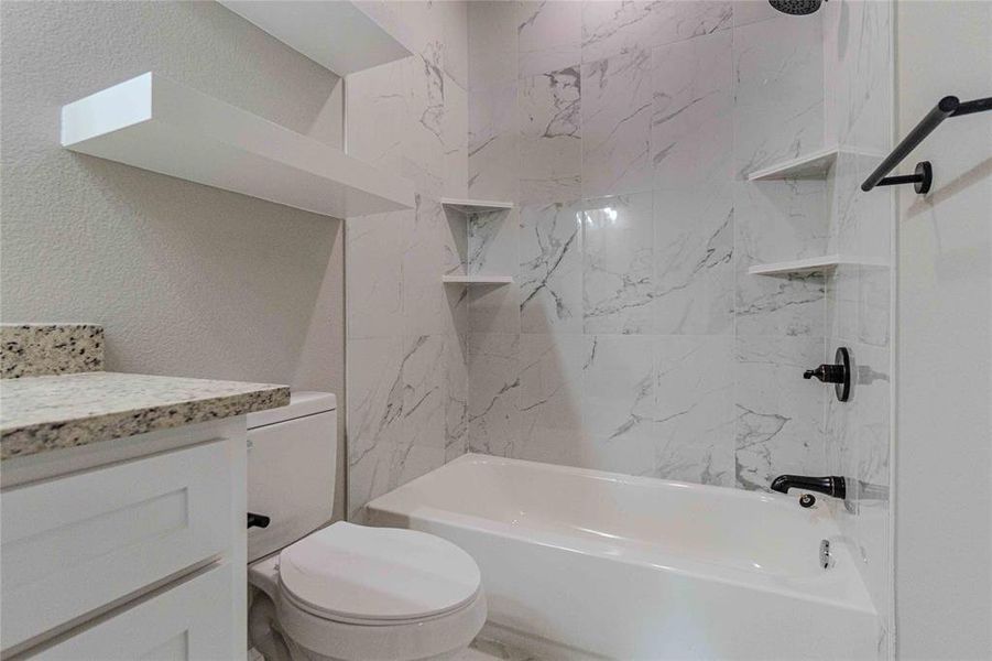 Full bathroom featuring vanity, tiled shower / bath, and toilet