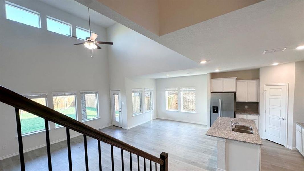 Kitchen with healthy amount of natural light, white cabinetry, light stone counters, light wood-style floors, and a towering ceiling Kitchen with healthy amount of natural light, white cabinetry, light stone counters, light wood-style floors, and a towering ceiling