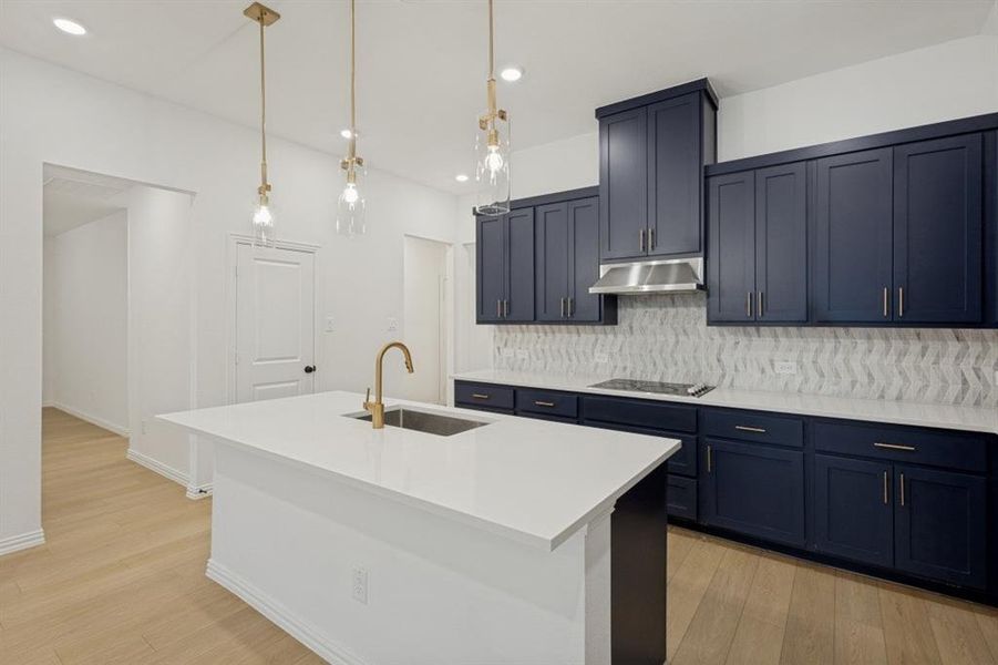 Kitchen featuring dark blue cabinetry with brushed nickel hardware, white countertops, and a patterned tile backsplash