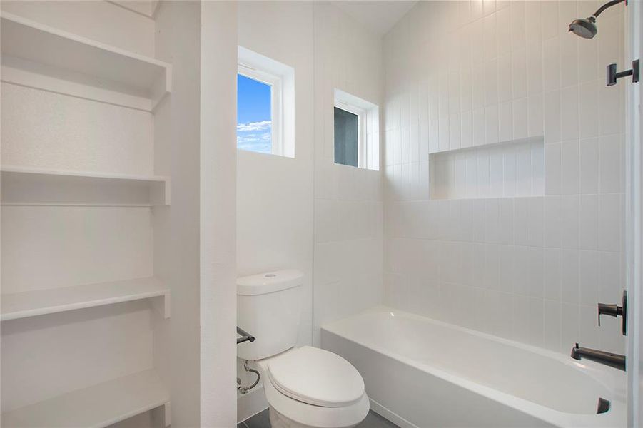 Bathroom with tiled shower / bath and toilet