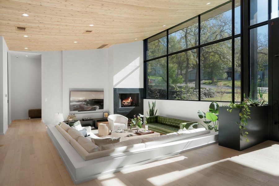 The unique sunken living room accommodates a 72" TV and features a custom steel fireplace and shelving nestled in a Venetian plaster wall.