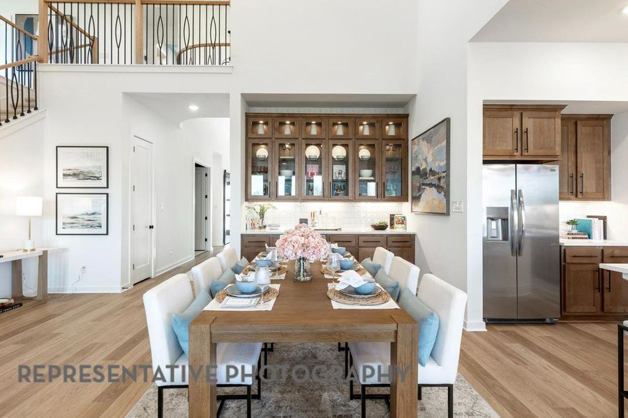 Dining area with light wood finished floors, a towering ceiling, recessed lighting, and stairway Dining area with light wood finished floors, a towering ceiling, recessed lighting, and stairway