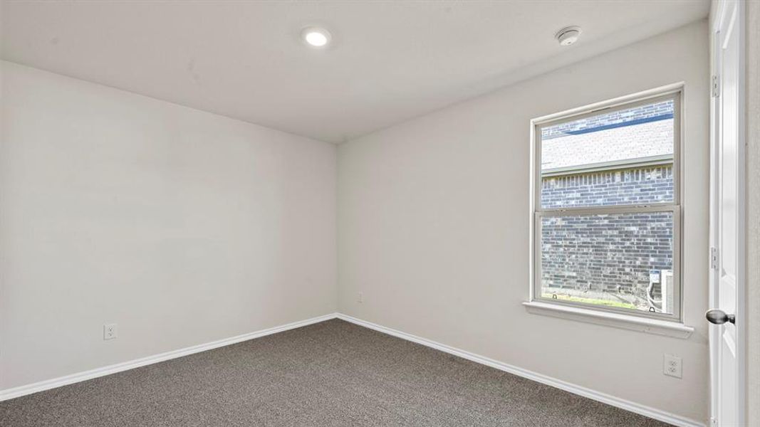 Unfurnished room featuring baseboards and dark carpet