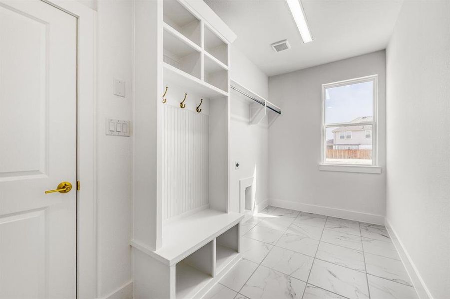 Mudroom featuring light marble finish flooring and baseboards