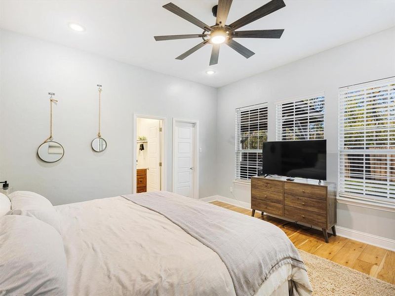 Bedroom featuring light wood finished floors, ceiling fan, recessed lighting, ensuite bath, and multiple windows