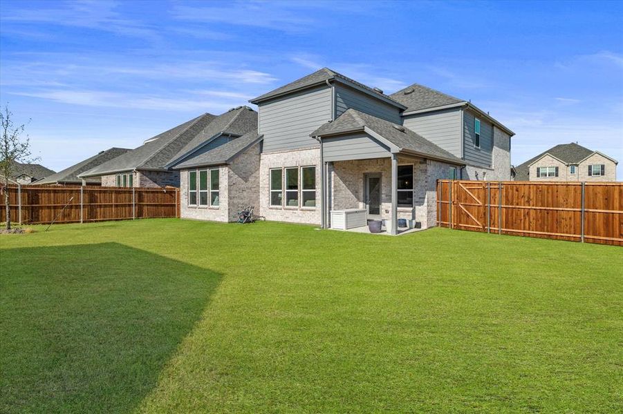 Rear view of house featuring a patio area, brick siding, and a fenced backyard