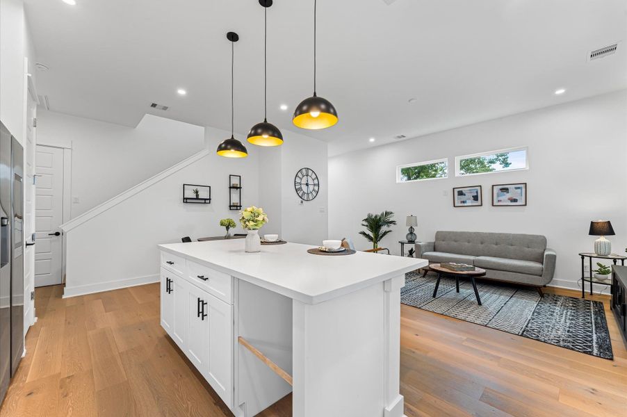 This centrally positioned kitchen island serves as a stylish anchor within the open-concept layout, offering clear sightlines to the dining area, living space, and the backyard beyond. Its placement encourages seamless interaction, whether prepping meals or entertaining guests, while natural light pours in through the nearby windows. The island’s sleek design and functional surface make it a hub of activity, framed by elegant finishes tying together comfort and sophistication.