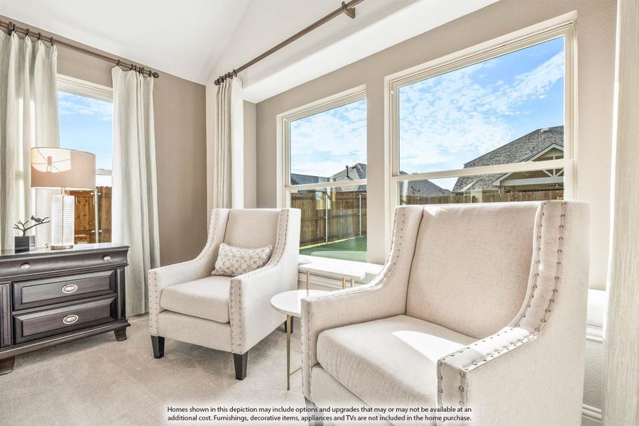 Sitting area with two beige accent chairs, vaulted ceiling, large windows, and carpet flooring