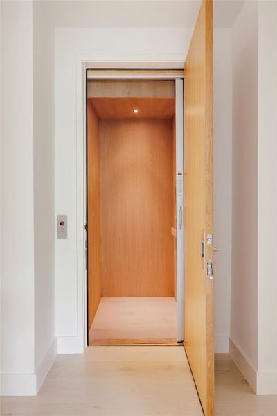 Hallway featuring elevator and wood finished floors Hallway featuring elevator and wood finished floors