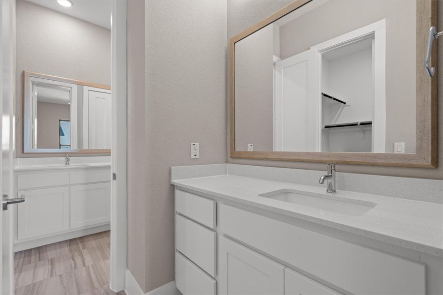 A well-lit primary bathroom with dual vanities and contemporary fixtures. A well-lit primary bathroom with dual vanities and contemporary fixtures.