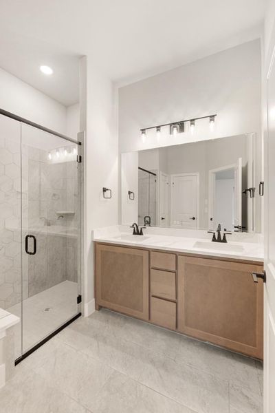 Bathroom with double sink vanity, large mirror, and glass walk-in shower with hexagon tile walls