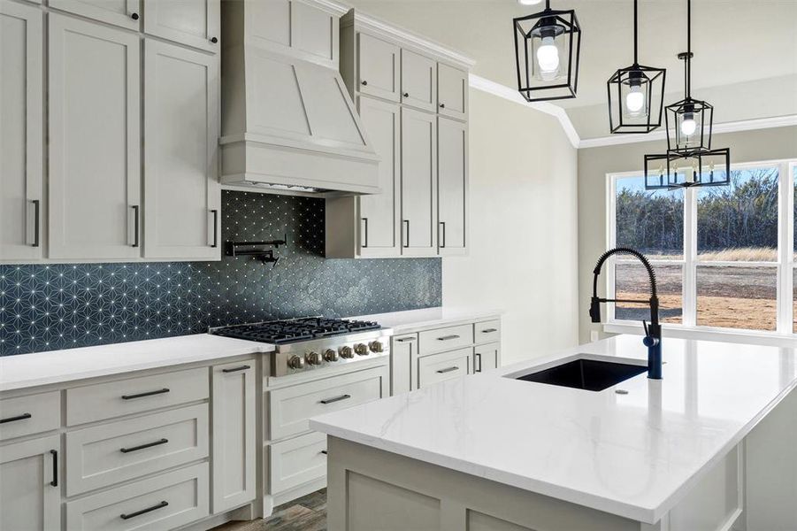 Kitchen with tasteful backsplash, stainless steel gas stovetop, sink, custom range hood, and a center island with sink