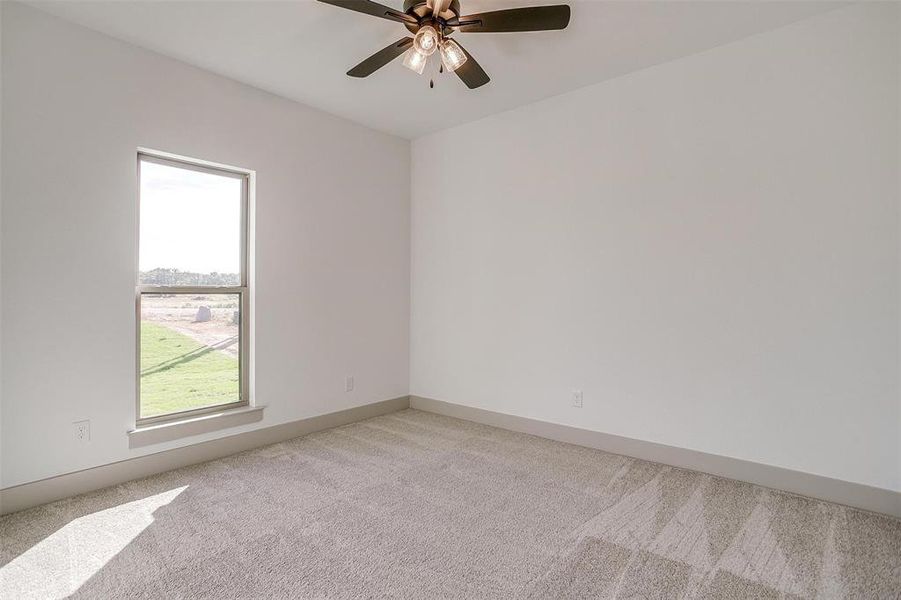 Carpeted empty room featuring ceiling fan